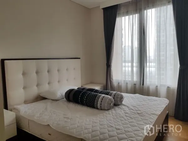 Condominium for rent in Ratchathewi, Bangkok - Cozy bedroom with tufted headboard, large windows with sheer curtains and a city outlook.