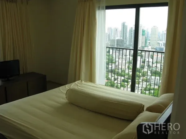 公寓 出租在Khlong Toei, Bangkok - 卧室配大窗与阳台，可眺望素坤逸城市天际线。