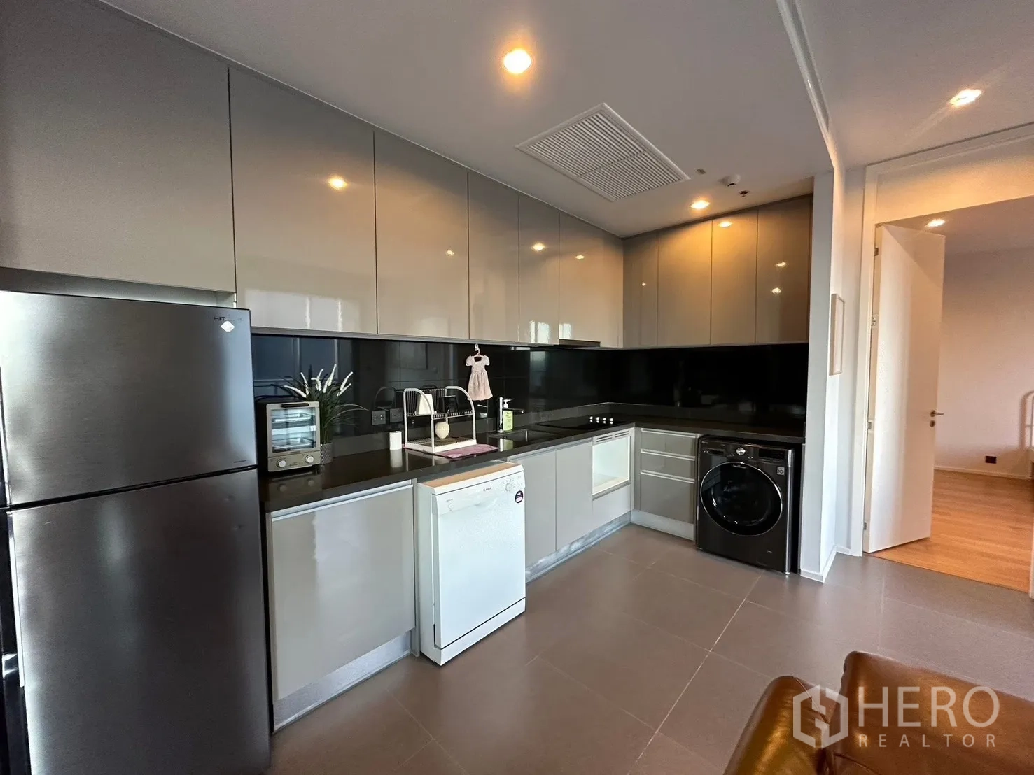 Condominium for rent or sale in Chatuchak, Bangkok - Sleek kitchen with glossy cabinets, fridge, dishwasher, and washer.