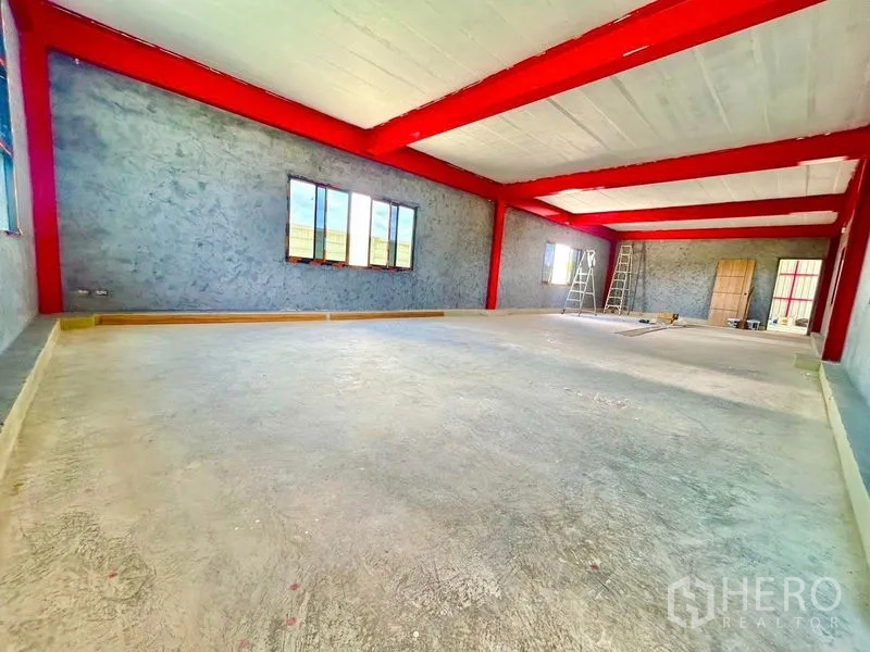 Warehouse for rent in Lam Luk Ka, Pathum Thani - Unfinished mezzanine office space with windows and red beams inside the warehouse.
