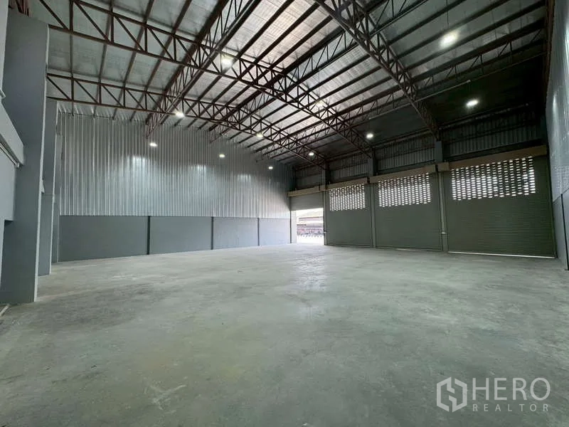 Warehouse for rent in Bang Phli, Samut Prakan - Open-plan warehouse space with steel truss roof and roller shutter loading doors