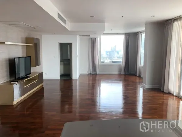公寓 出租在Khlong Toei, Bangkok - 宽敞客厅，抛光木地板、落地窗与内置电视柜，享城市景观