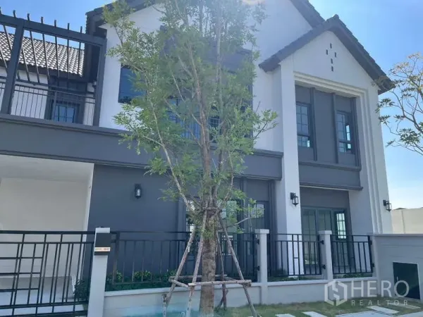 บ้าน ให้เช่าในBang Phli, Samut Prakan - หน้าบ้านเดี่ยวสองชั้นสไตล์โมเดิร์น โทนขาวเทา พร้อมรั้วและสนามหญ้า บางพลี