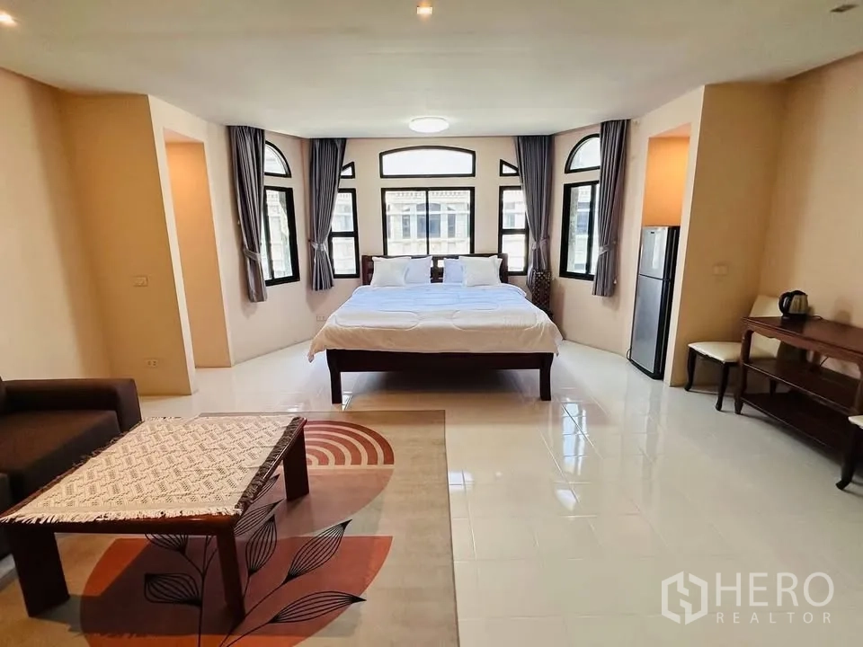 Townhouse for rent - Large master bedroom with many windows, bed, area rug, sofa, desk, and refrigerator.
