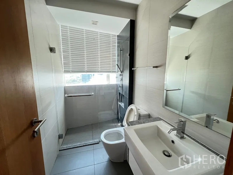 Condominium for rent in Khlong Toei, Bangkok - Bathroom with window, walk-in shower, vanity and toilet.