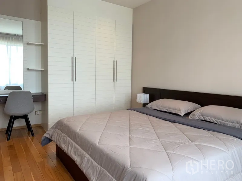 Condominium for rent in Khlong Toei, Bangkok - Bedroom with hardwood floors, upholstered headboard and full-height wardrobe.
