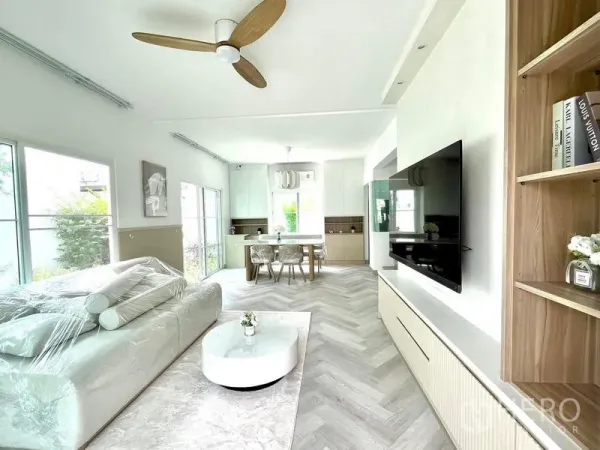 Detached House for rent - Open-plan living and dining area with large windows, ceiling fan, built-in TV wall and herringbone flooring.