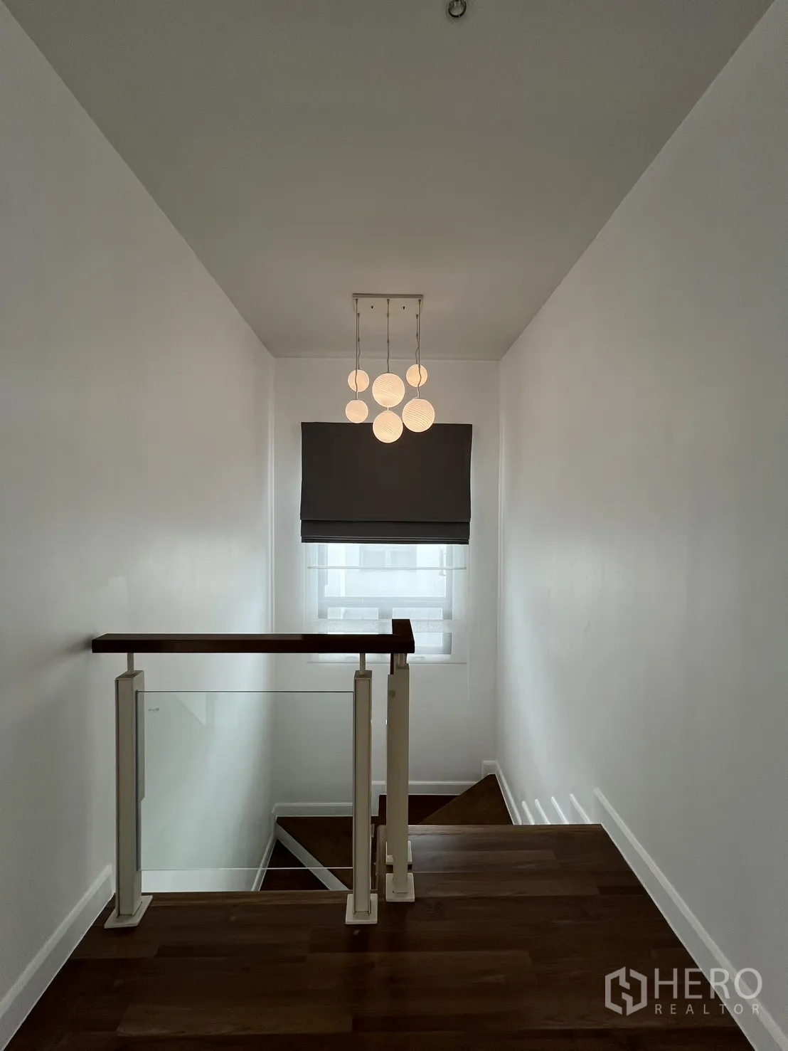 Detached House for rent in Bang Kapi, Bangkok - Stair landing with modern pendant light and glass-balustrade railing.