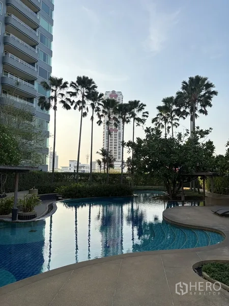 公寓 for rent in Khlong San, Bangkok - 曲线设计的室外泳池，周围环绕棕榈树与景观花园。
