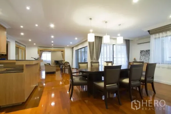 Condominium for rent in Watthana, Bangkok - Dining area with round table, pendant lights and open kitchen cabinetry.