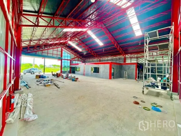Warehouse for rent in Lam Luk Ka, Pathum Thani - Open warehouse floor with red beams, skylights and a mezzanine-ready office section.