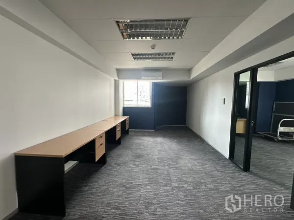 办公空间 出租在Watthana, Bangkok - 私密工作区，长条内置办公桌，灰色地毯与格栅照明，旁有窗户。