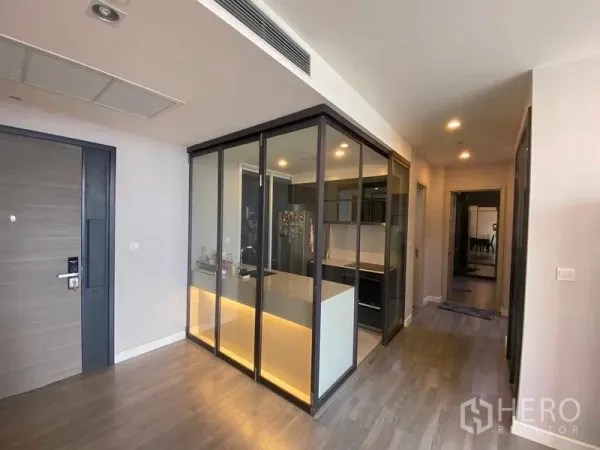 Condominium for rent or sale in Bang Rak, Bangkok - Modern condo entry with glass-enclosed kitchen island, warm lighting and wood floors.