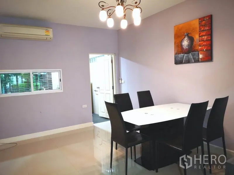 Townhouse for rent in Suan Luang, Bangkok - Dining room with six-seat table, chandelier lighting and wall art.