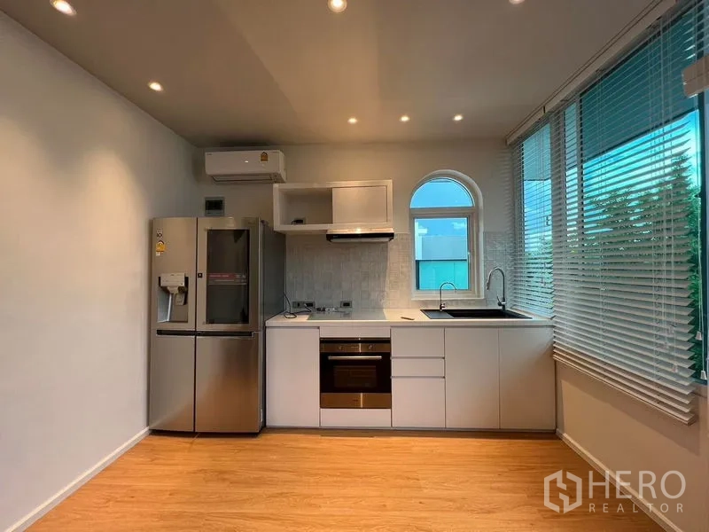 Detached House for sale in Saphan Sung, Bangkok - Light-filled secondary kitchen with white cabinetry, built-in oven and double-door fridge.