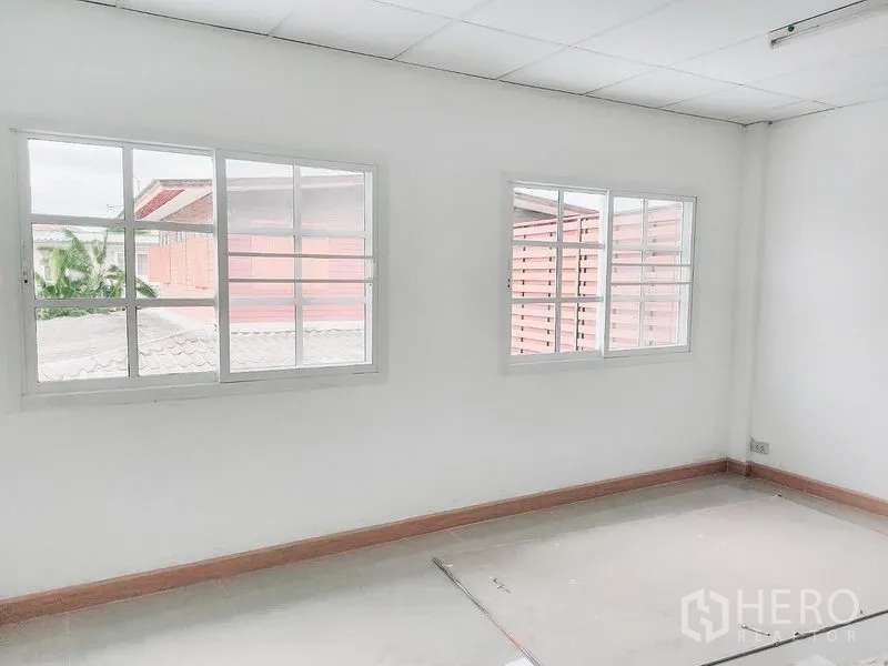 Townhouse for rent in Chatuchak, Bangkok - Sunlit bedroom with two sliding windows and neutral tile flooring.