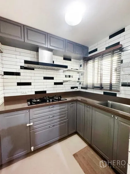 Townhouse for rent in Phra Khanong, Bangkok - U-shaped grey kitchen with subway tile backsplash and gas hob.