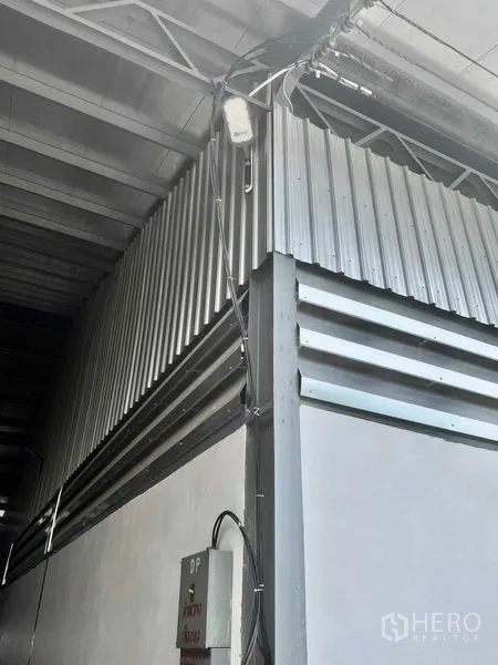 Warehouse for rent in Mueang Samut Prakan, Samut Prakan - Detail of corrugated metal cladding and an electrical panel at the warehouse corner.