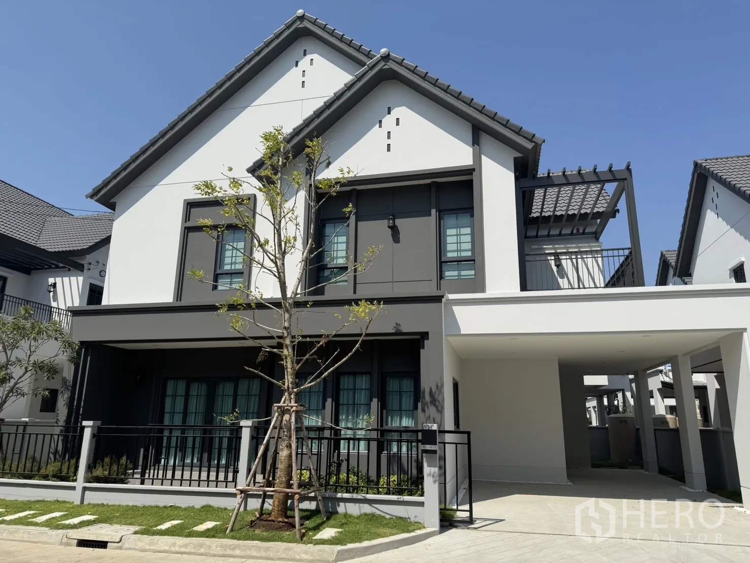 Detached House for rent in Bang Phli, Samut Prakan - Modern two-storey detached house exterior with carport, balcony terrace, lawn and gated fence.