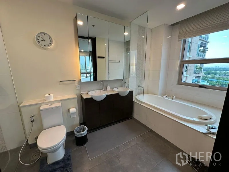 公寓 出租在Yan Nawa, Bangkok - 宽敞浴室，双台盆、窗边浴缸与城市景色。
