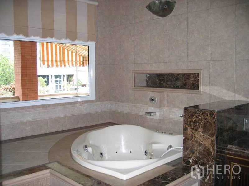 Detached House for rent in Watthana, Bangkok - Bathroom with a corner jacuzzi tub set in marble and a large window.