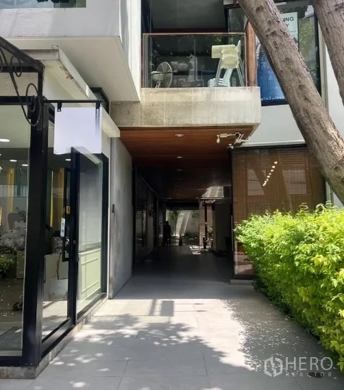 พื้นที่ขายปลีก ให้เช่าในWatthana, Bangkok - ทางเดินค้าปลีกมีร่มเงา หน้าร้านกระจกสมัยใหม่ ฝ้าไม้ และทางเท้าริมพุ่มไม้