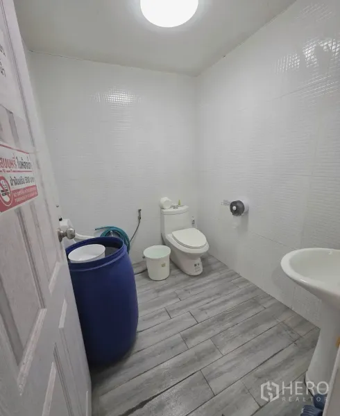 Warehouse for rent in Khlong Toei, Bangkok - Clean tiled restroom with toilet and pedestal sink inside the warehouse.