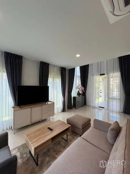 Detached House for rent in Bang Kapi, Bangkok - Bright living room with sofa set, TV console and full-height curtains.