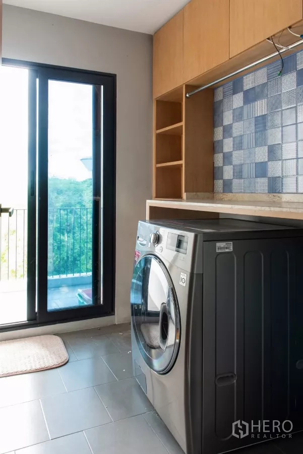 Townhouse for rent in Lat Phrao, Bangkok - Laundry room with front-load washer and access to a balcony.