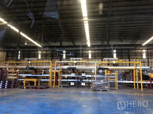 Warehouse for sale in Wang Noi, Phra Nakhon Si Ayutthaya - Spacious warehouse interior with steel trusses, bright strip lighting, and yellow racking systems.
