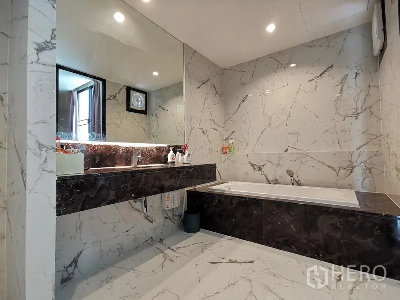 Townhouse for sale - Modern marble bathroom with long vanity, oversized mirror and a built-in bathtub.