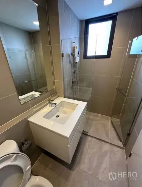 Townhouse for rent in Lat Phrao, Bangkok - Contemporary bathroom featuring a glass shower, large mirror and window.