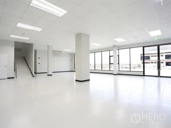 Factory for rent in Bang Pakong, Chachoengsao - Bright office space inside the factory featuring tiled floors, large windows and a staircase.