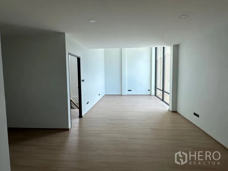 Warehouse for sale in Lam Luk Ka, Pathum Thani - Upper-floor open-plan office with wood-look flooring and tall window.