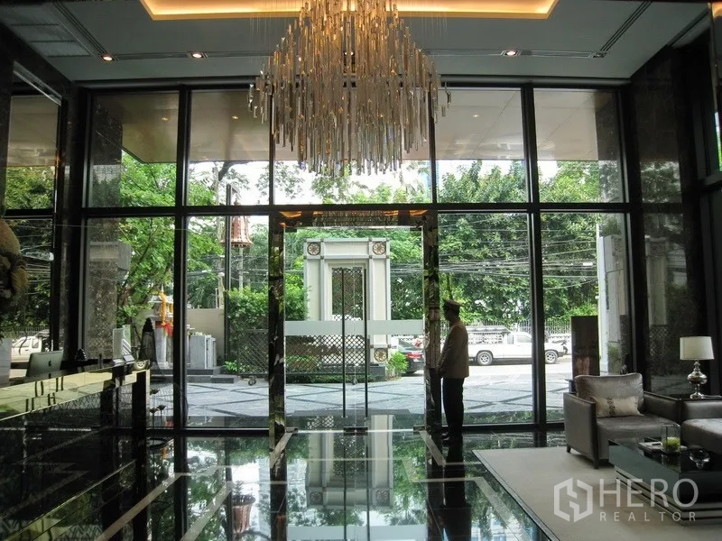 公寓 出租在Watthana, Bangkok - 大堂入口配水晶吊灯与大理石地面，整面落地窗对望绿意。