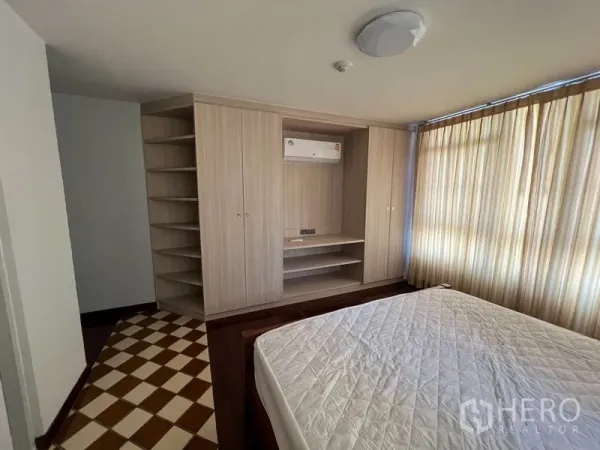 Condominium for rent or sale in Watthana, Bangkok - Bedroom featuring built-in wardrobe, open shelving, air conditioner and curtained windows.