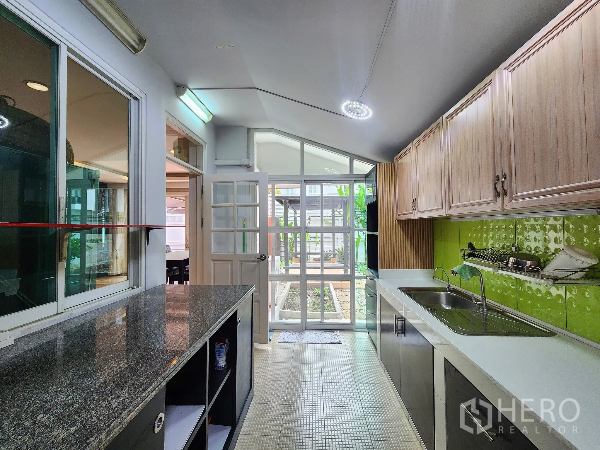 Detached House for rent in Bang Kapi, Bangkok - Bright kitchen with granite countertop, double sink and green backsplash.
