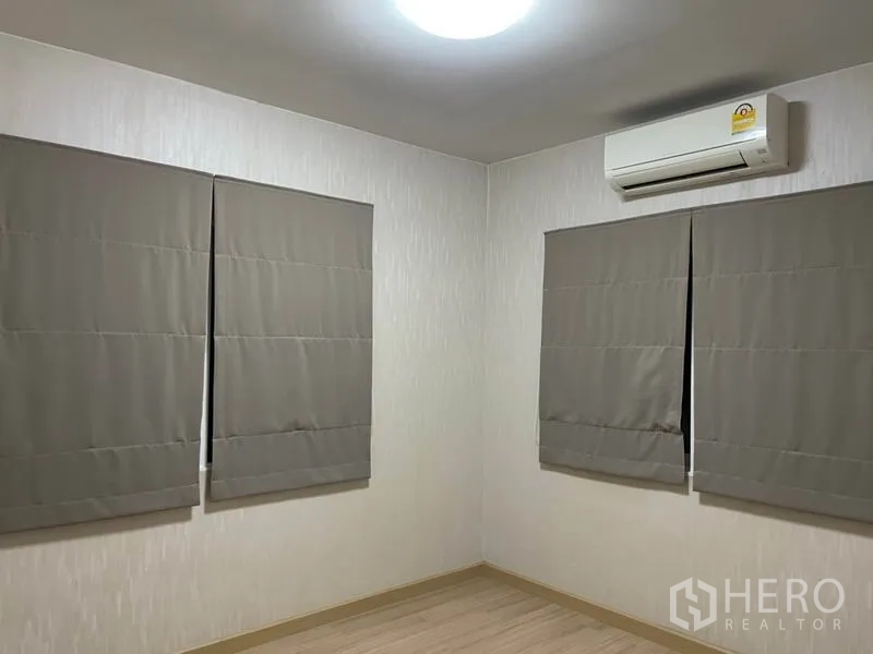 Detached House for sale in Khlong Toei, Bangkok - Guest bedroom with roller blinds and wall-mounted air conditioner.
