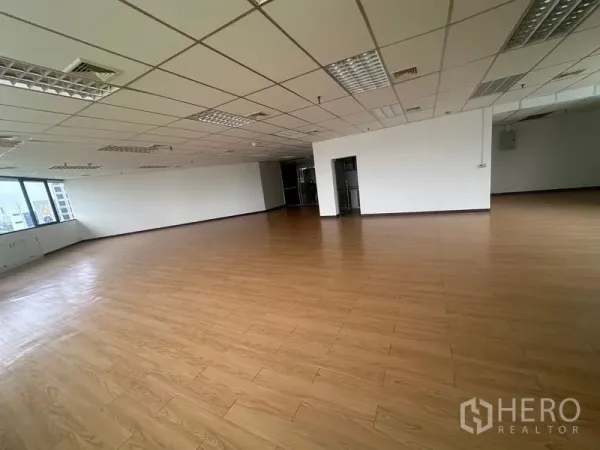 Office Space for rent in Bang Rak, Bangkok - Large office interior with wood-style floor, white walls, central column and wraparound windows for natural light