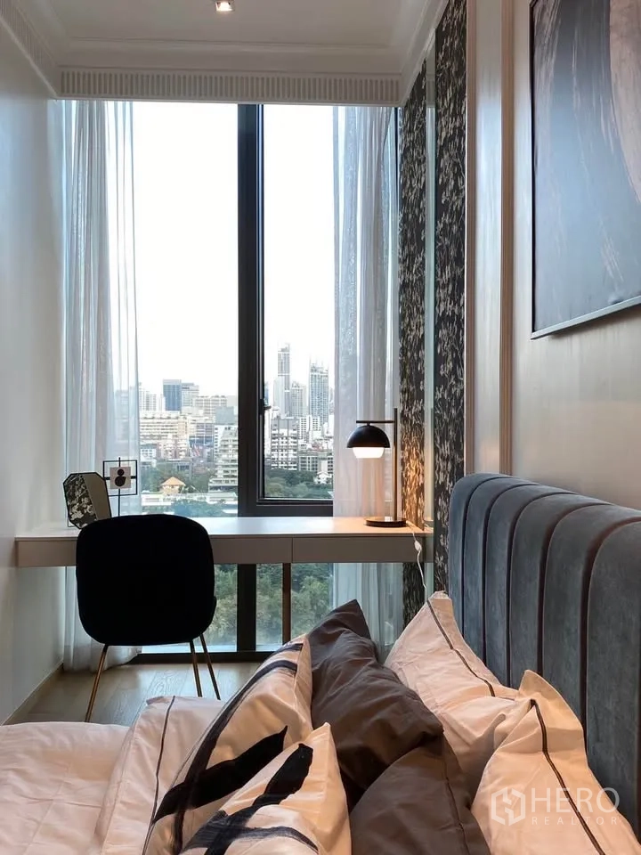 公寓 for rent in Pathum Wan, Bangkok - 靠床视角可见内置书桌与台灯，落地窗外是城市天际线。