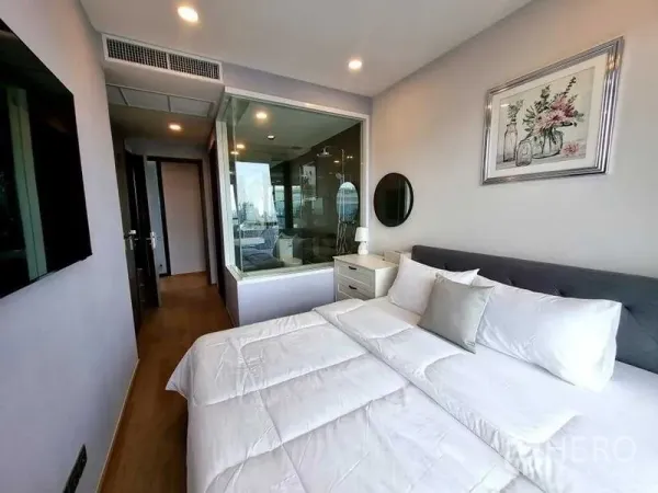 公寓 出租在Bang Rak, Bangkok - 卧室配玻璃隔断通向浴室，筒灯与木地板营造温馨感。
