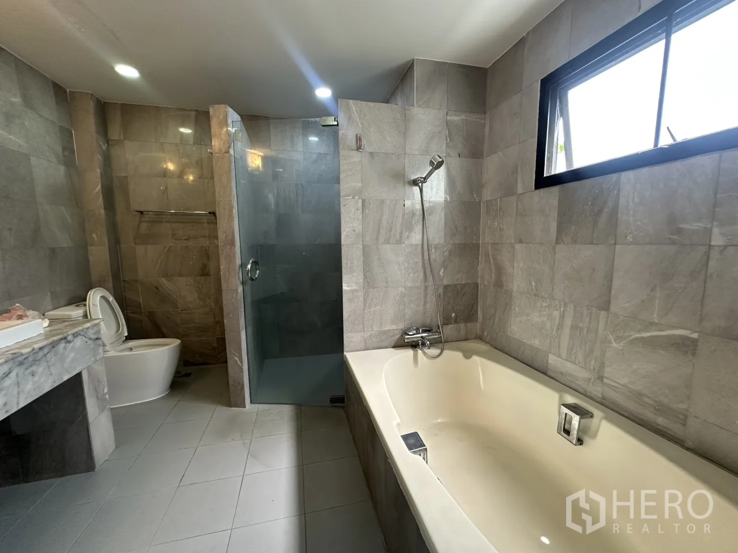 Detached House for rent in Watthana, Bangkok - Bright bathroom showing bathtub beside window and separate shower.