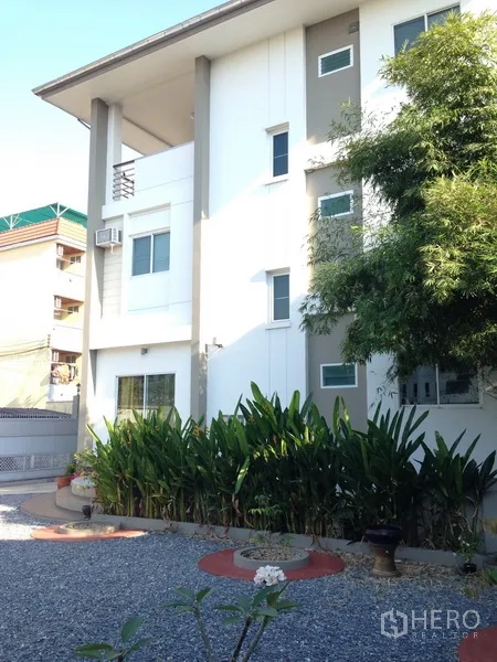 Detached House for sale in Phra Khanong, Bangkok - Modern multi-storey white detached house with green landscaping and a gravel yard in Phra Khanong.