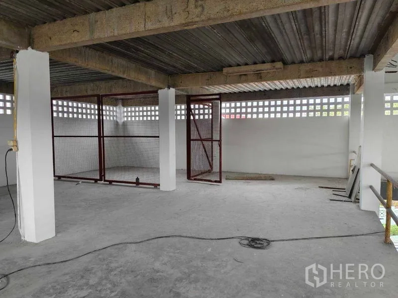 Warehouse for rent in Phra Khanong, Bangkok - Mezzanine zone with red mesh cage storage beneath a metal roof.