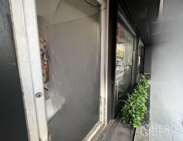 店屋 出租 - 一层橱窗近景，带花槽与人行道。