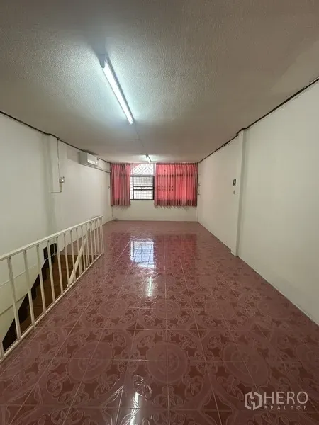 Shophouse for rent or sale in Phra Khanong, Bangkok - Upper floor room with pink ceramic tiles, window with red curtains, and stair railing.