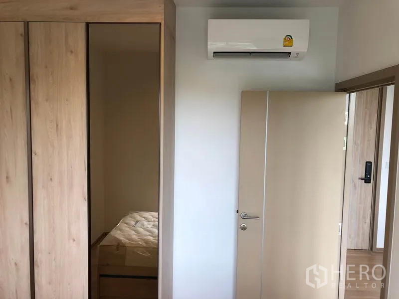 Condominium for rent in Watthana, Bangkok - Closet and air conditioner in a bright bedroom with neutral finishes.