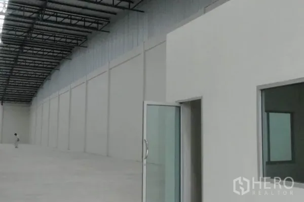 Warehouse for rent in Phra Nakhon Si Ayutthaya - Spacious warehouse interior with high steel roof, concrete floor, and glass-fronted office rooms.