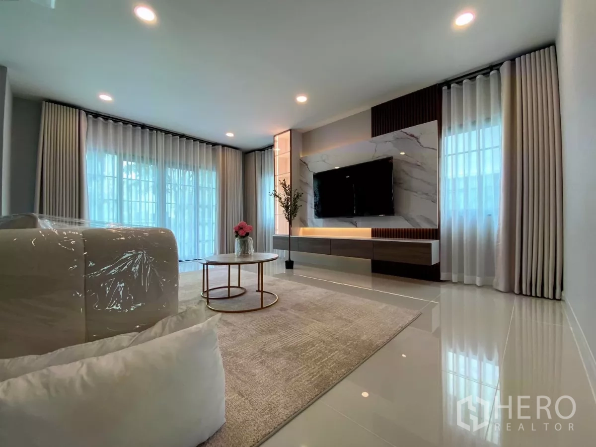 Detached House for rent in Bang Phli, Samut Prakan - Bright living room with large windows, marble TV feature wall and recessed lighting.