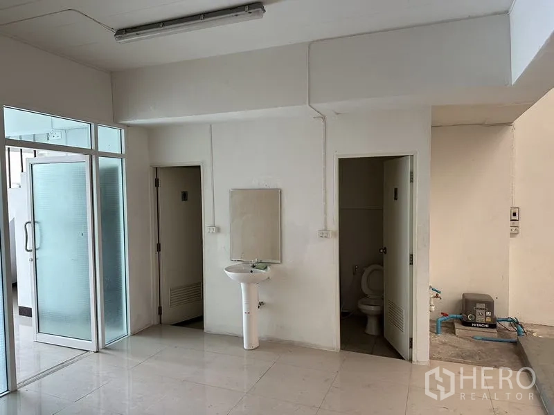 Factory for rent in Bang Sao Thong, Samut Prakan - Utility area with two restrooms, pedestal sink and glass door access.